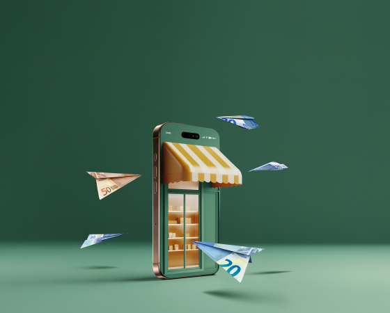 Representació conceptual d'un comerç electrònic sobre un fons verd. Un telèfon intel·ligent simula una botiga física amb un tendal de ratlles grogues i blanques i prestatgeries il·luminades al seu interior. Avions de paper fets amb bitllets de 20 i 50 euros volen al voltant del dispositiu.